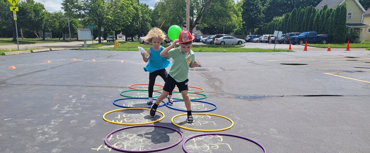 two young kids jumping in hula hoops on a parking lot 