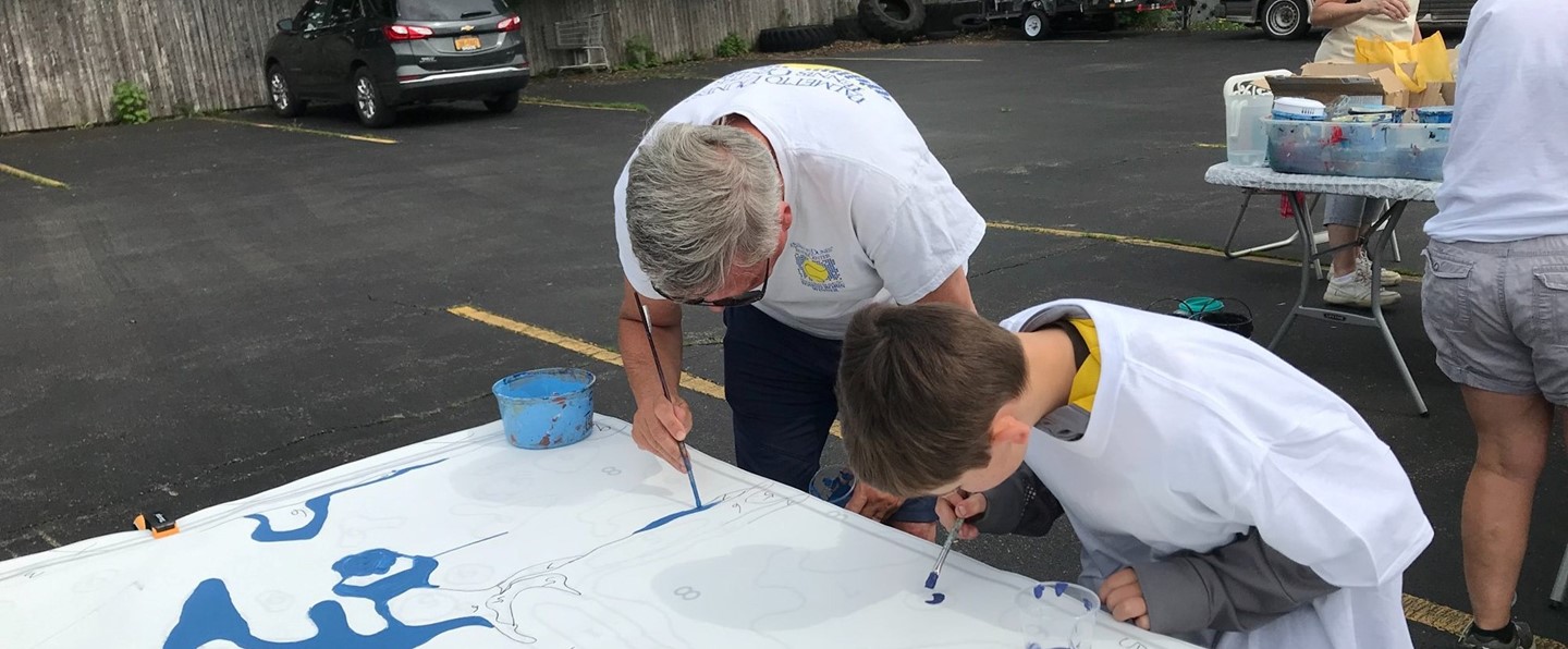 young boy and older man painting on a canvas