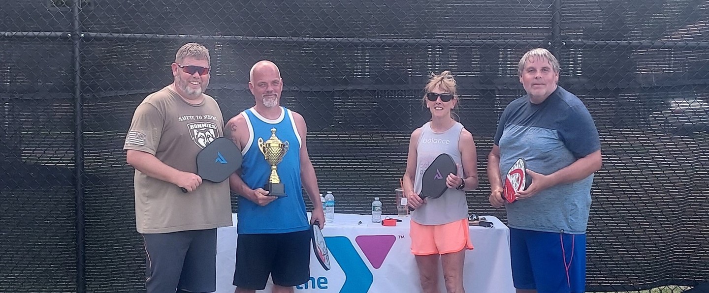 four pickleball players with a trophy