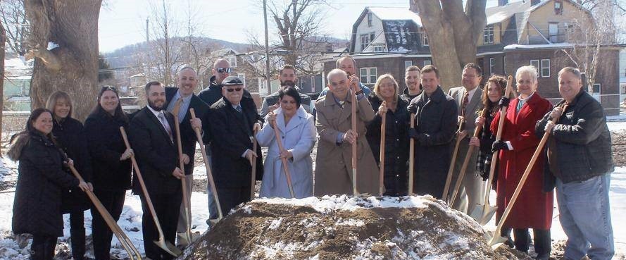 people holding shovels on mound of dirt